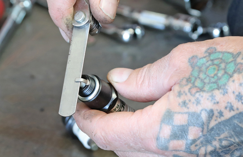 mechanic adjusts the specs of spark plug gap