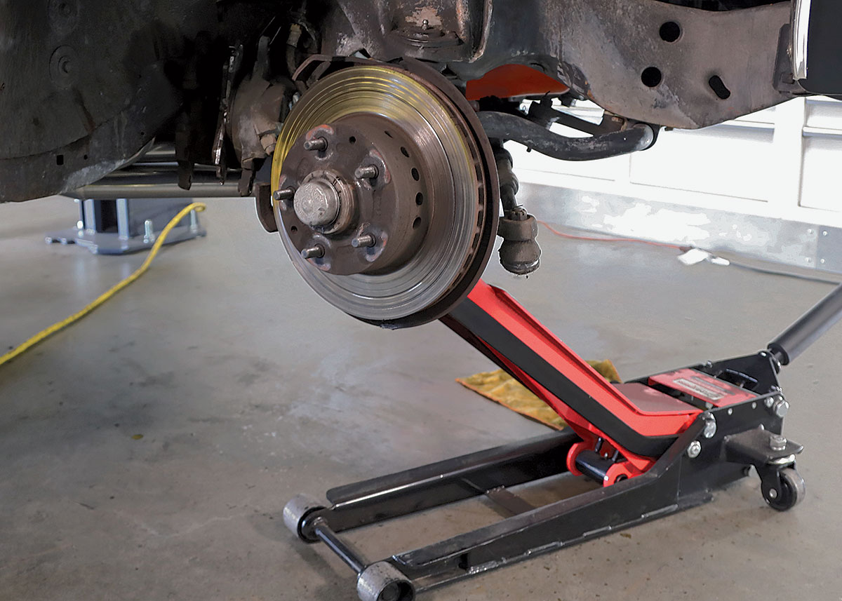 Floor jack supporting the lower control arm during separation