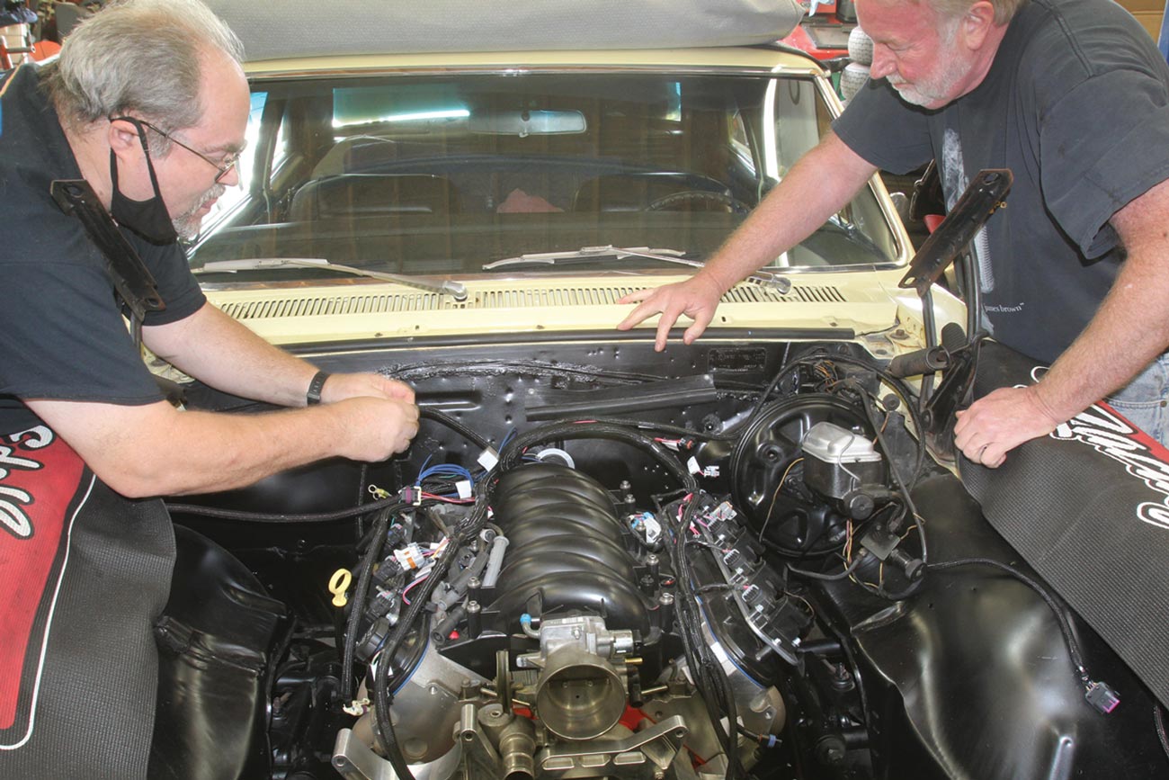 two mechanics lean over the exposed engine of a 1967 Chevelle 300