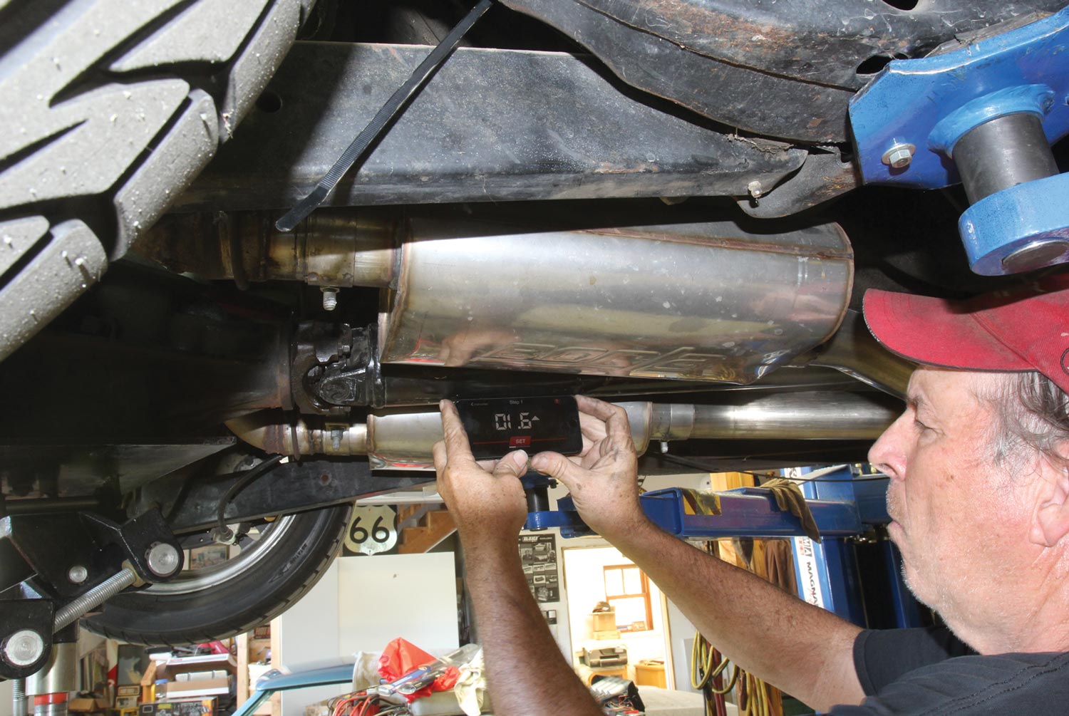 Mechanic uses a gauge beneath a car