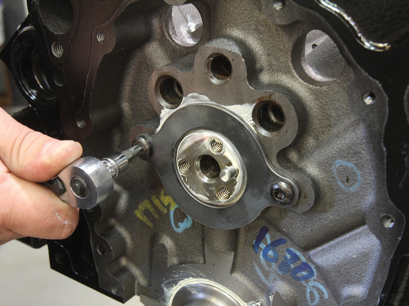 mechanic screws the camshaft retaining plate to the engine block