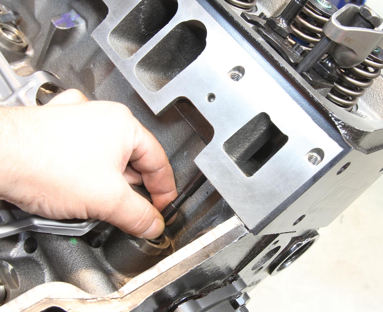 with one cylinder head torqued in place, one of the adjustable pushrods is installed along with the rocker arm