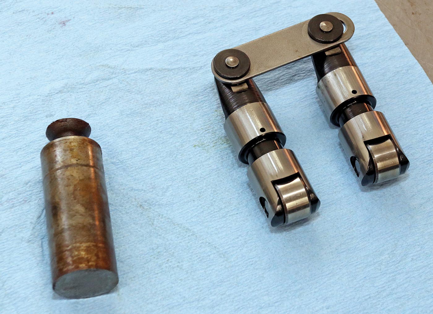 the stock solid flat-tappet lifter for this engine (left);  a pair of modern tie-bar roller lifters that Dorton managed to get to work (right)