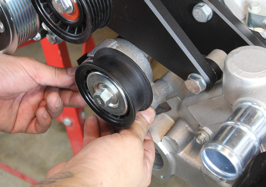 A spring-loaded belt tensioner is then installed on the water pump