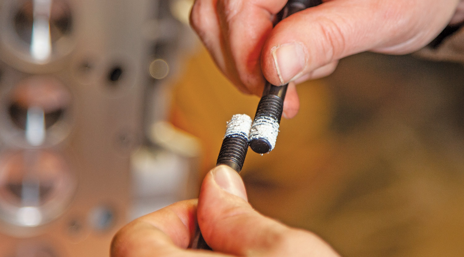 mechanic applies thread sealer to a new set of ARP head bolts