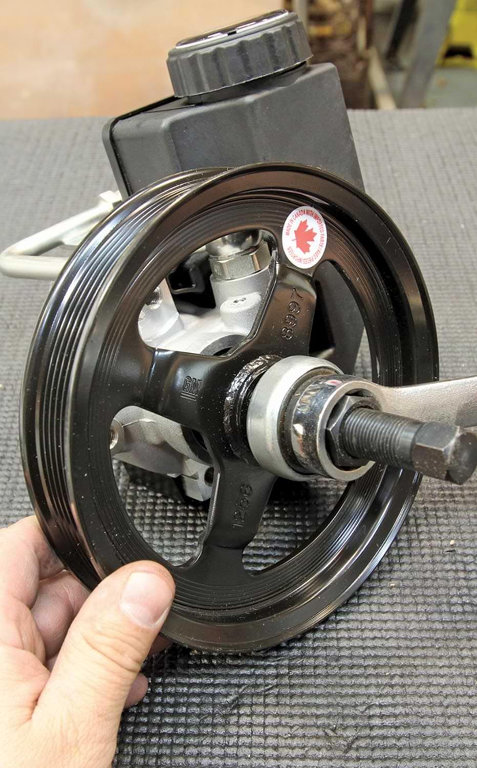 mechanic installs the power steering pulley to the power steering pump
