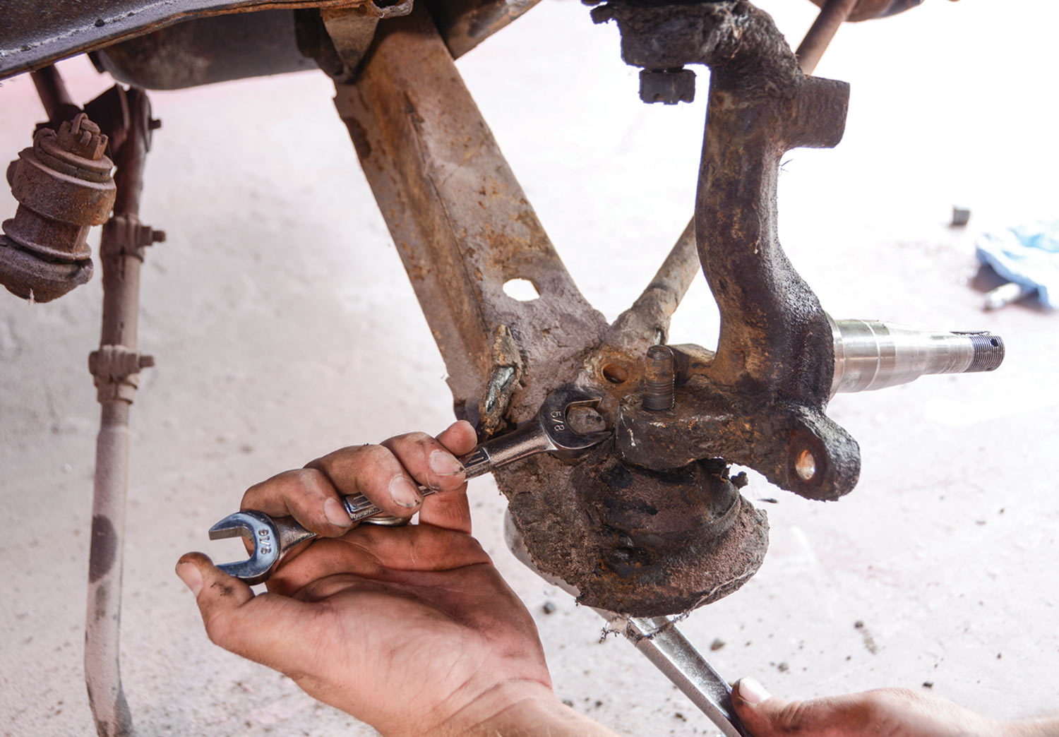 mechanic removes the two bolts and nuts that attach the rod to the lower control arm