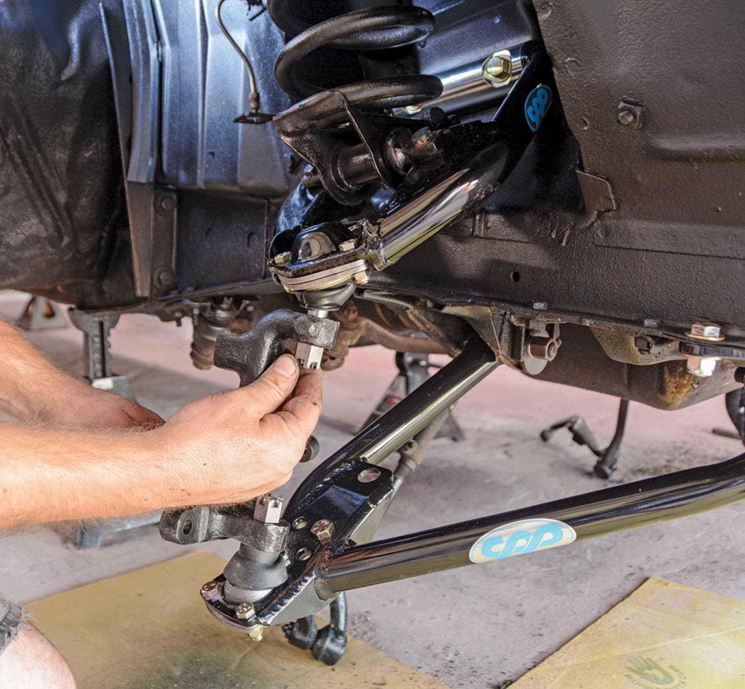 mechanic maneuvers the lower control arm and ball joints to fit properly