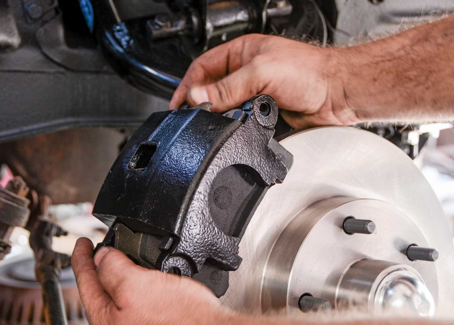 mechanic slides the brake caliper over the rotor