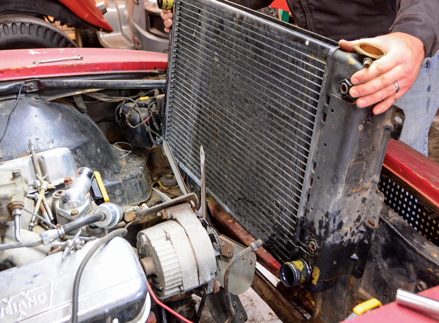 The first step in the makeover is draining the cooling system and removing the radiator. Then, we remove the mechanical fan, water pump, and alternator to provide access to clean the front of the engine block and cylinder heads.