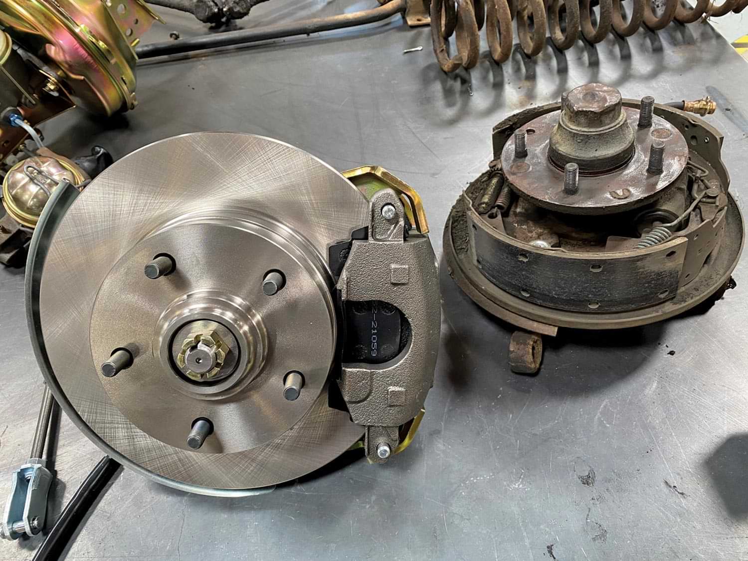 two brakes from POL’s disc brake upgrade kit for GM A-body lineup, one on its back and the other on its face, sit on a table top
