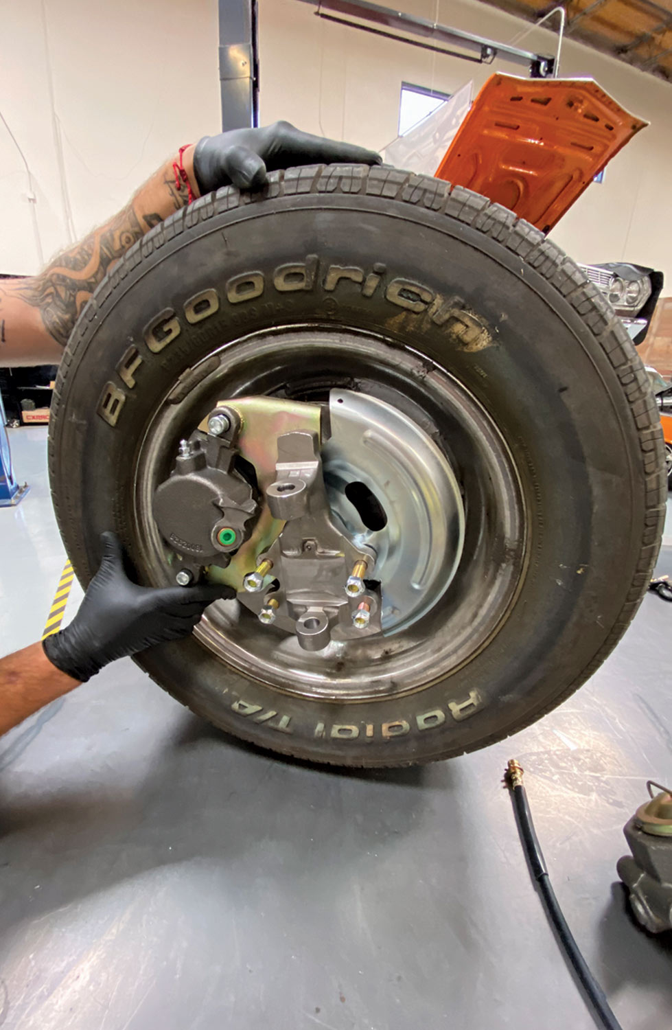 a mechanic works on a removed Chevelle wheel on a work table top