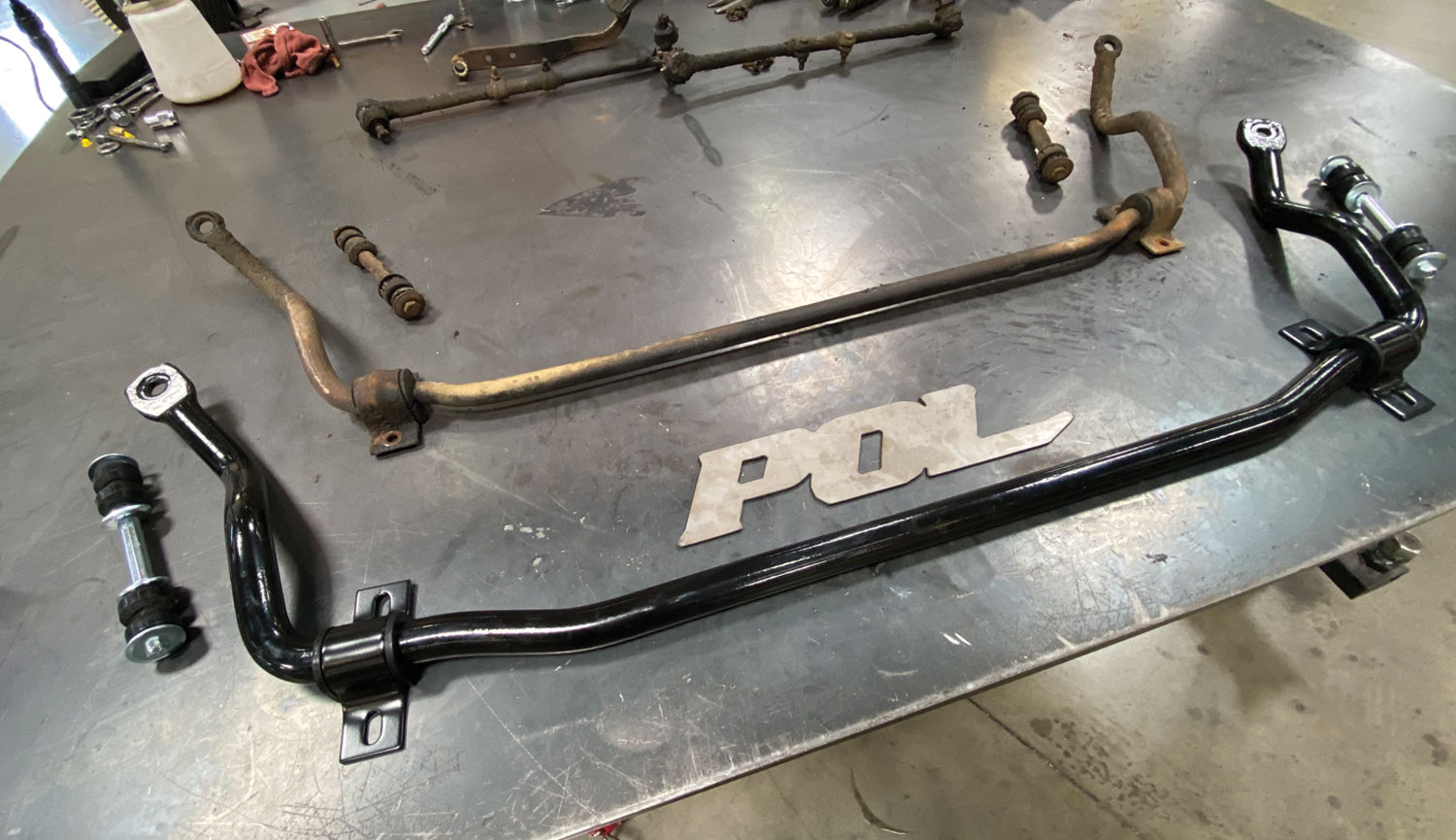 the old and new sway bars sit side by side on a table top