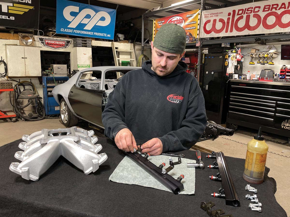 mechanic continues assembling the Holley EFI fuel rail with the supplied hardware using a ½-inch wrench