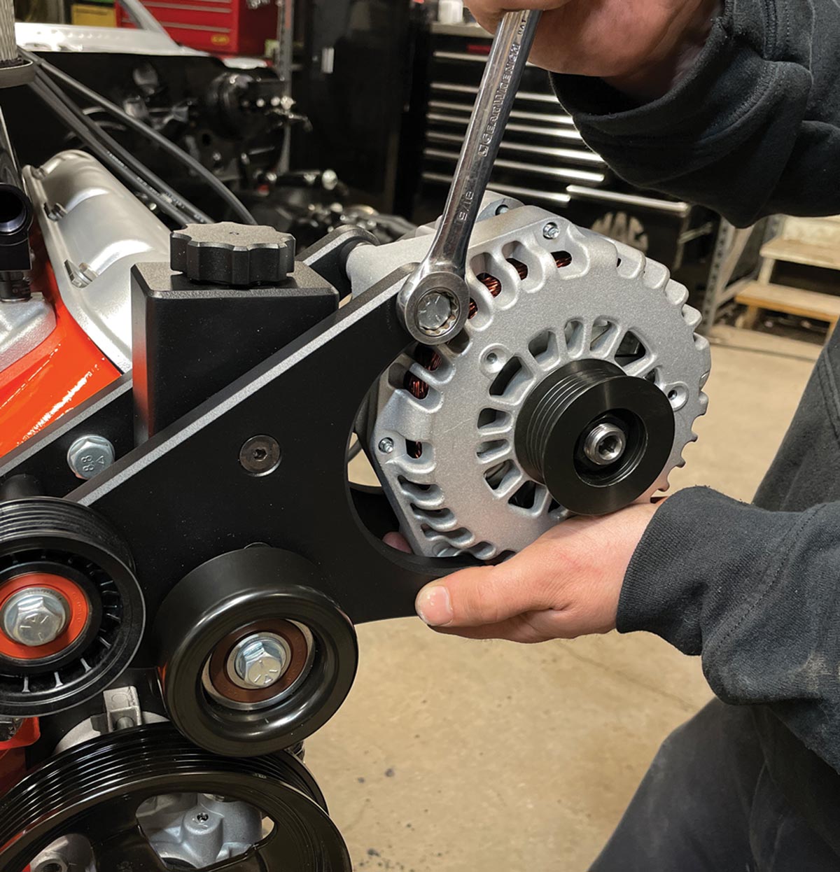 mechanic installs the Powermaster Performance 180-amp alternator with hex-head bolts, washers, and spacers
