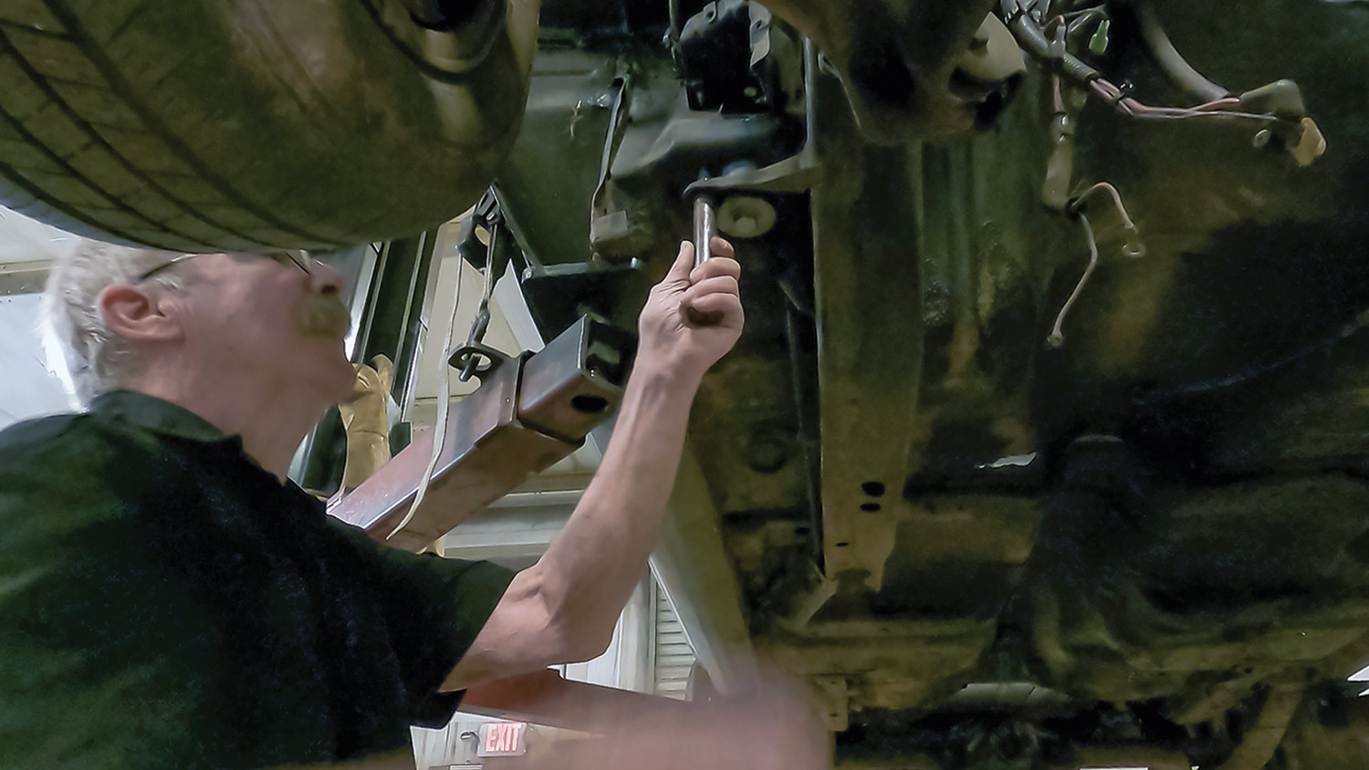mechanic uses locator pins to work on the subframe from beneath the lifted car