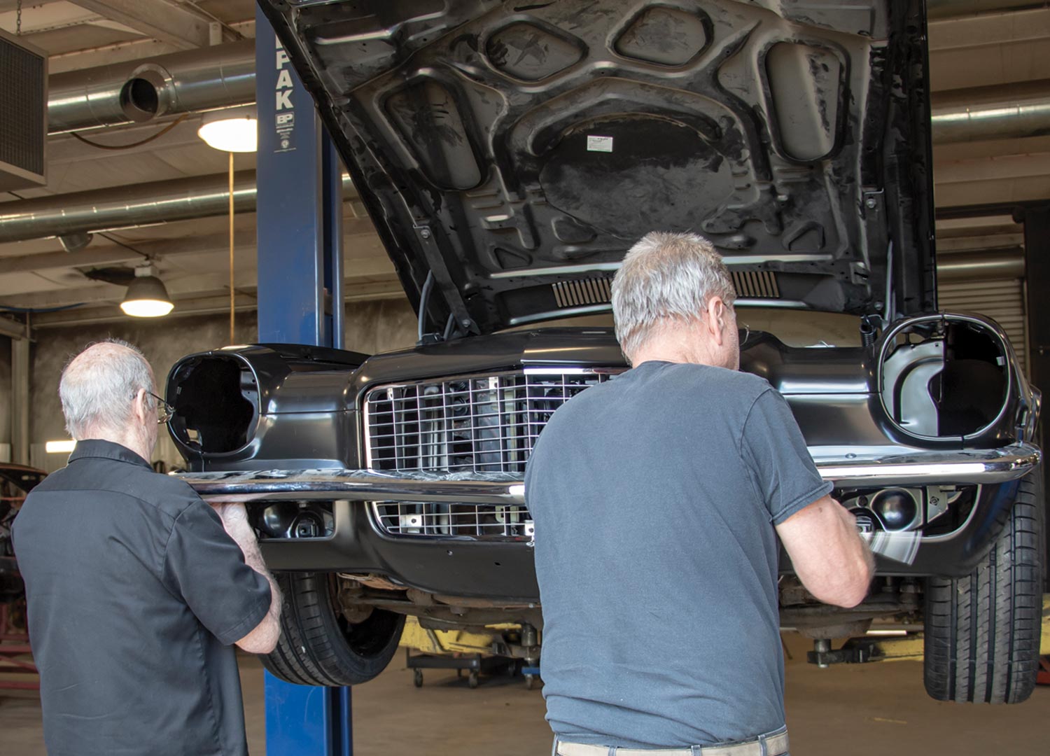 two mechanics holding the bumper to the lower valance in preparation for installation