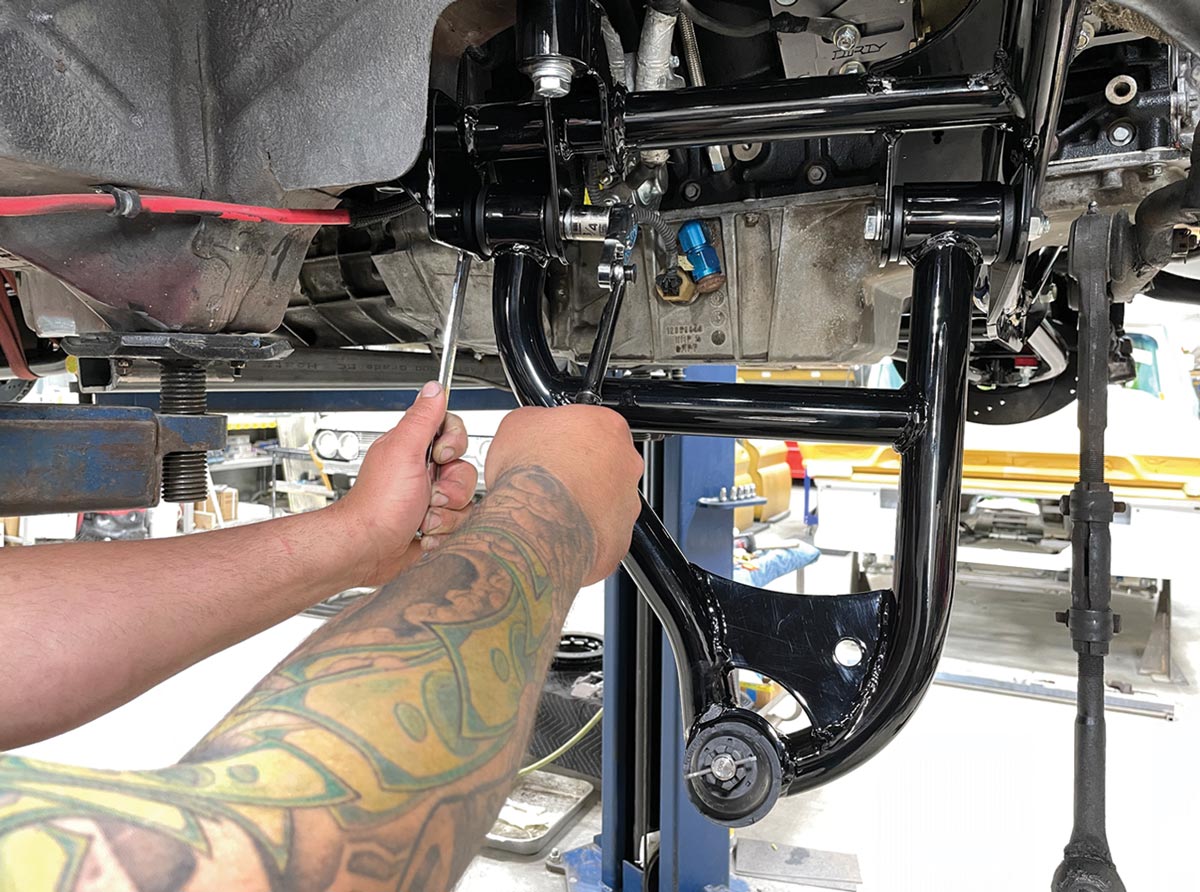 from beneath the lifted car, mechanic tightens the bolt on a Heidts tubular lower control arm
