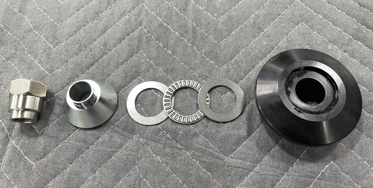 parts from the Strange Engineering double-adjustable coilover strut; from left to right: the upper strut assembly with the top spring seat, thrust washer, thrust bearing, thrust washer, thrust bearing cover/strut spacer, and strut top nut