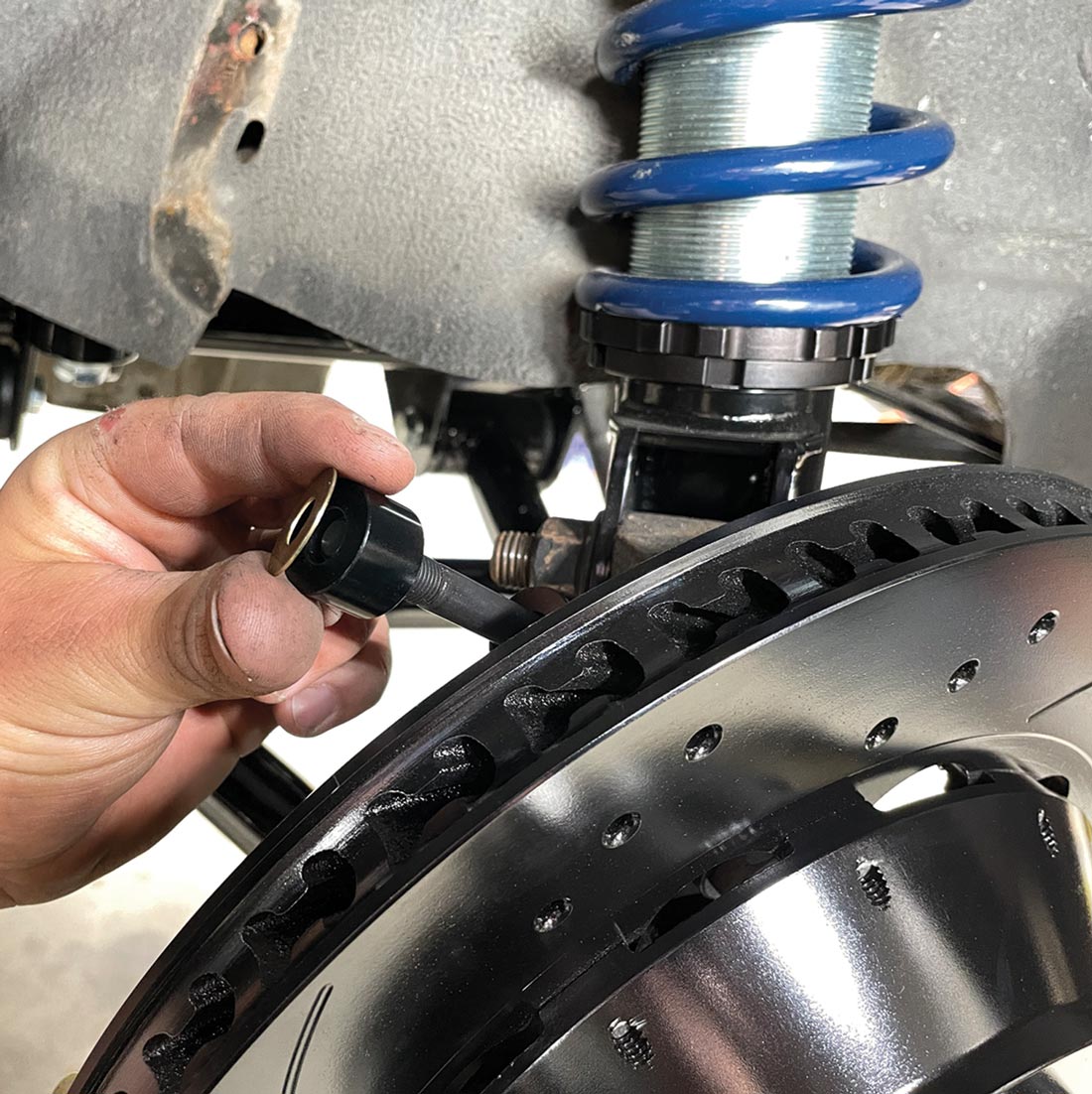 mechanic places a stud with a shim onto the caliper mounting bracket