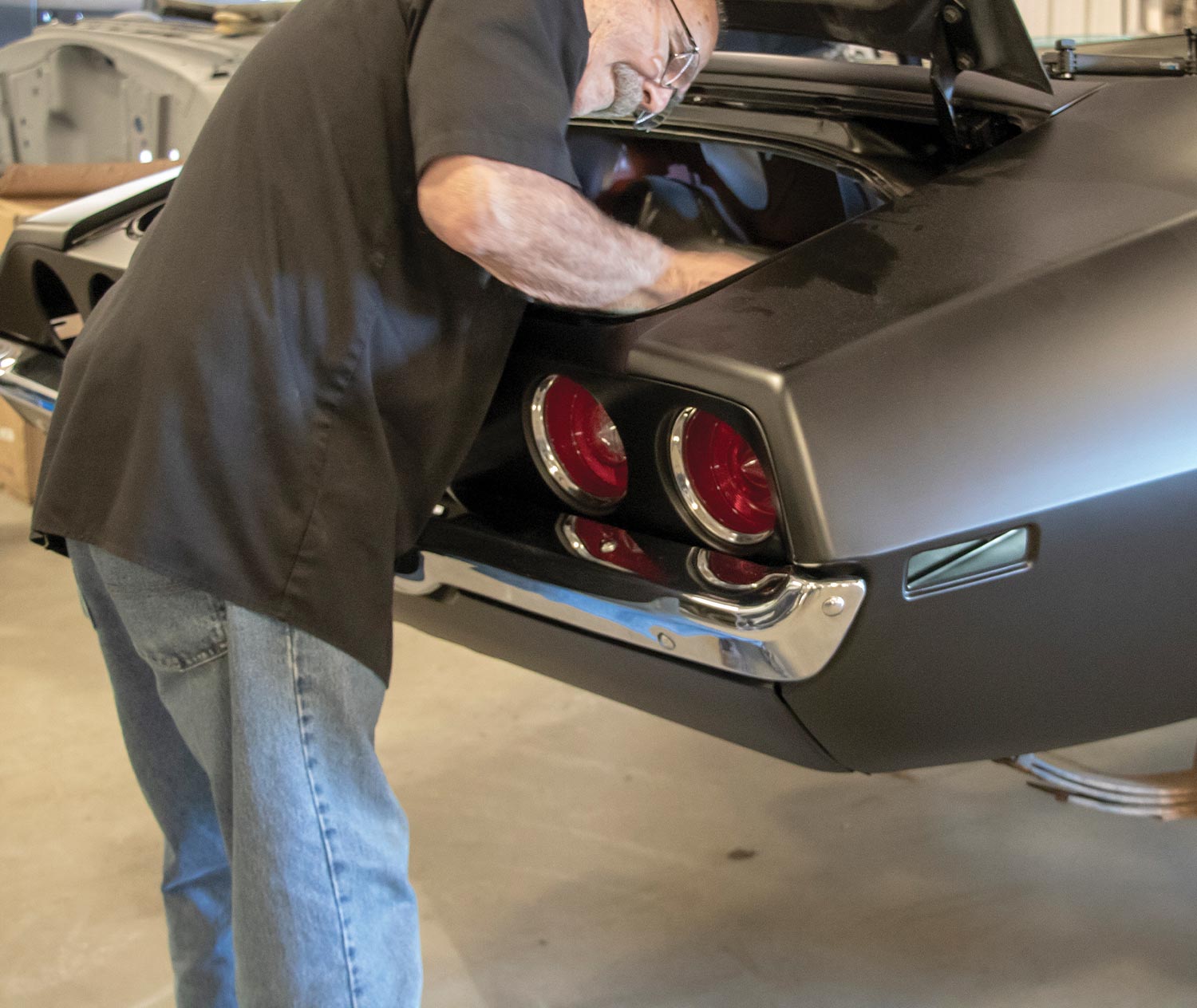 mechanic lines up the taillight housing from inside the trunk