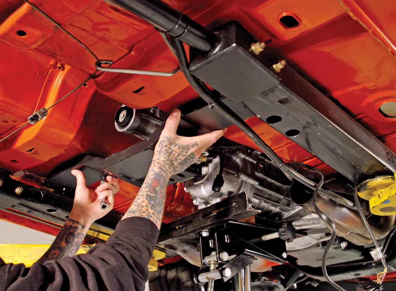 mechanic installs a crossmember on the lifted Camaro