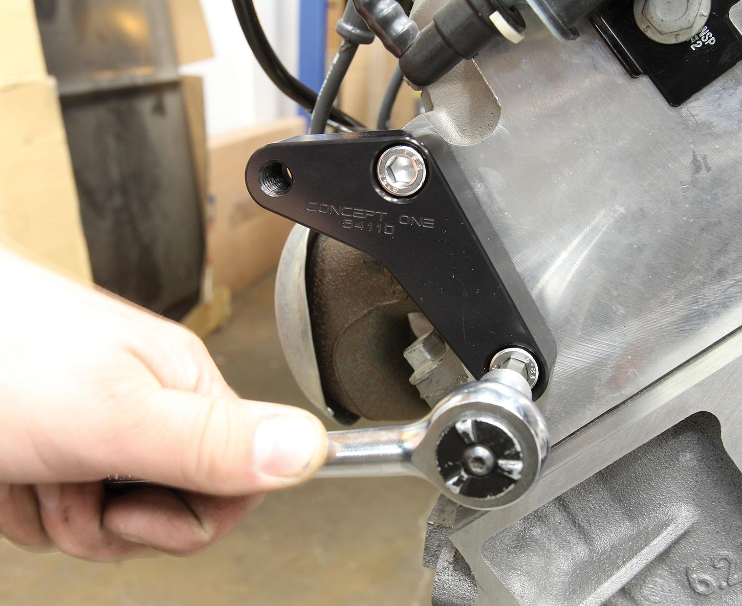 an M10 fastener is tightened on the A/C compressor mount bracket