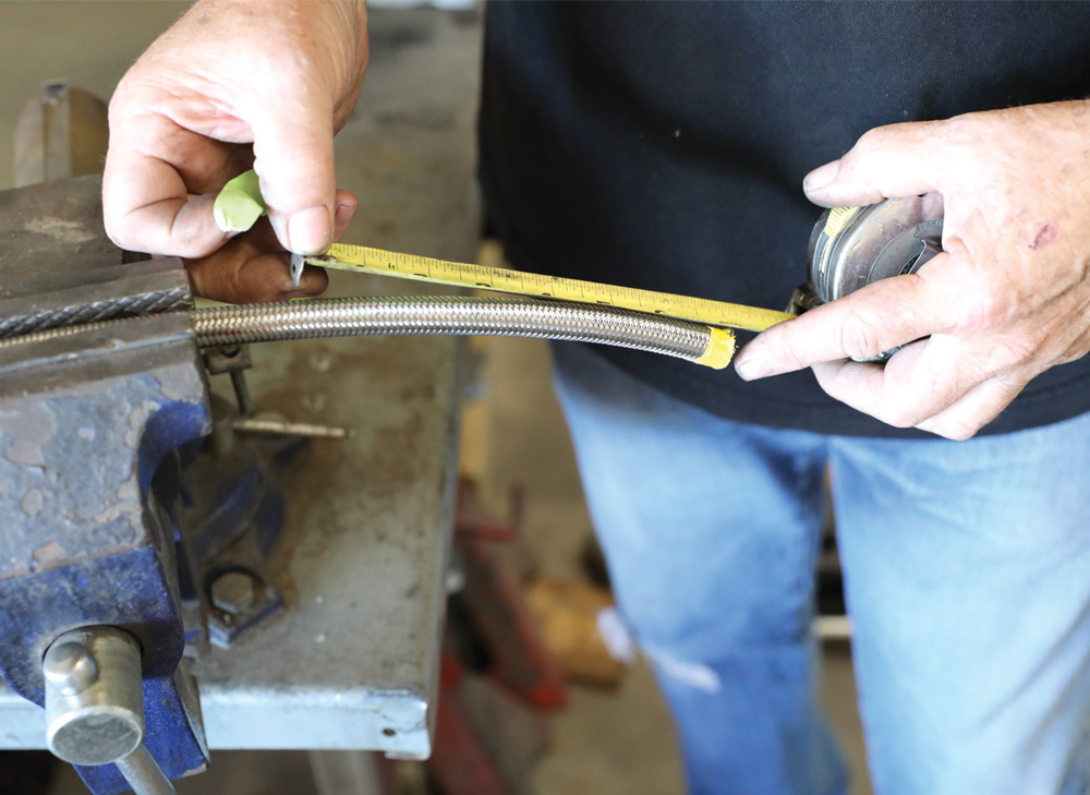 Terry begins the process of connecting all the components of the fuel system by measuring each length of hose. He wraps the areas to be cut in electrical tape to prevent the braided strands from fraying, then makes a clean slice with a cut-off wheel. 