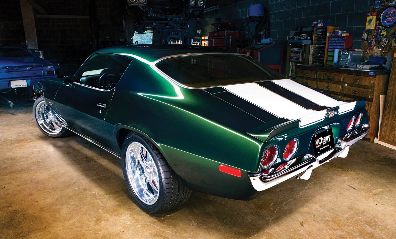 rear passenger side of a green '71 Camaro with white stripes parked in a garage