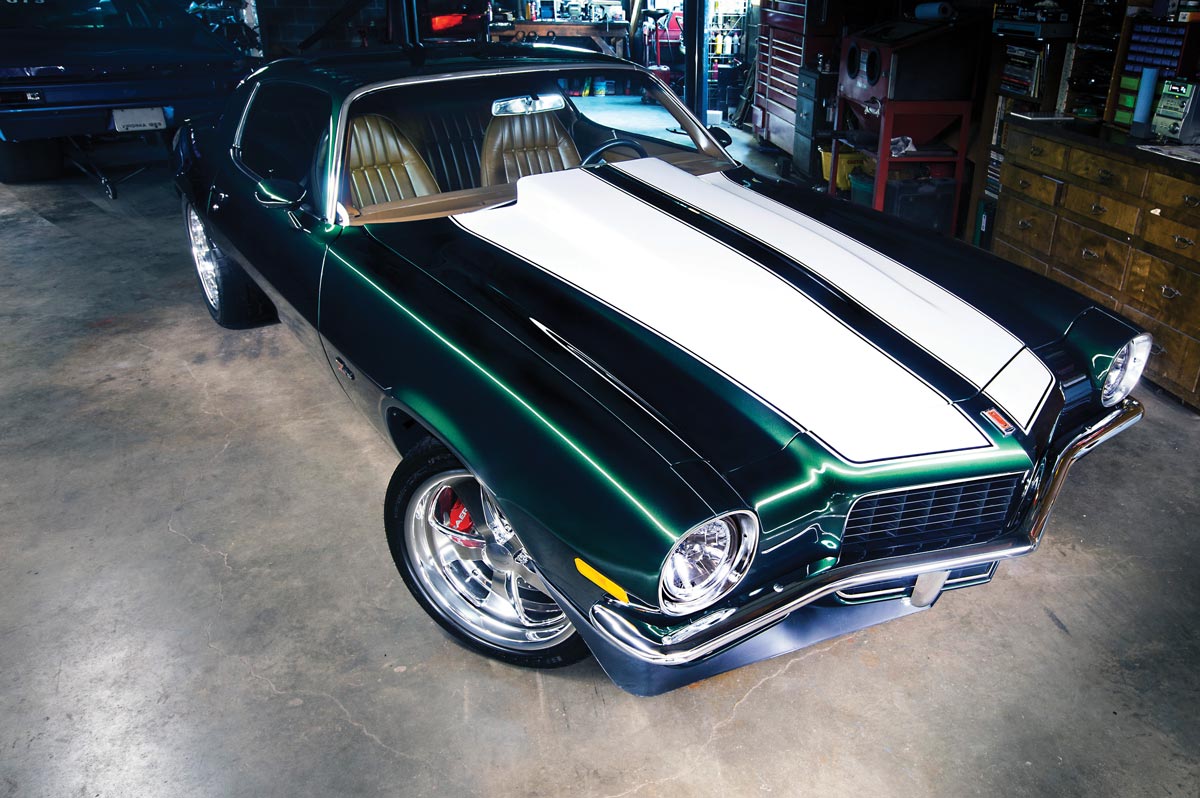 green '71 Camaro with white stripes parked in a garage