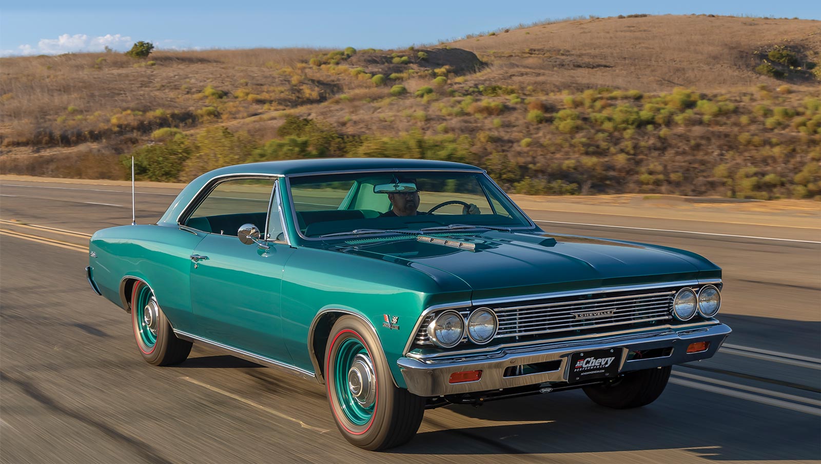 Metallic teal '66 Chevelle Malibu on road with hills in background