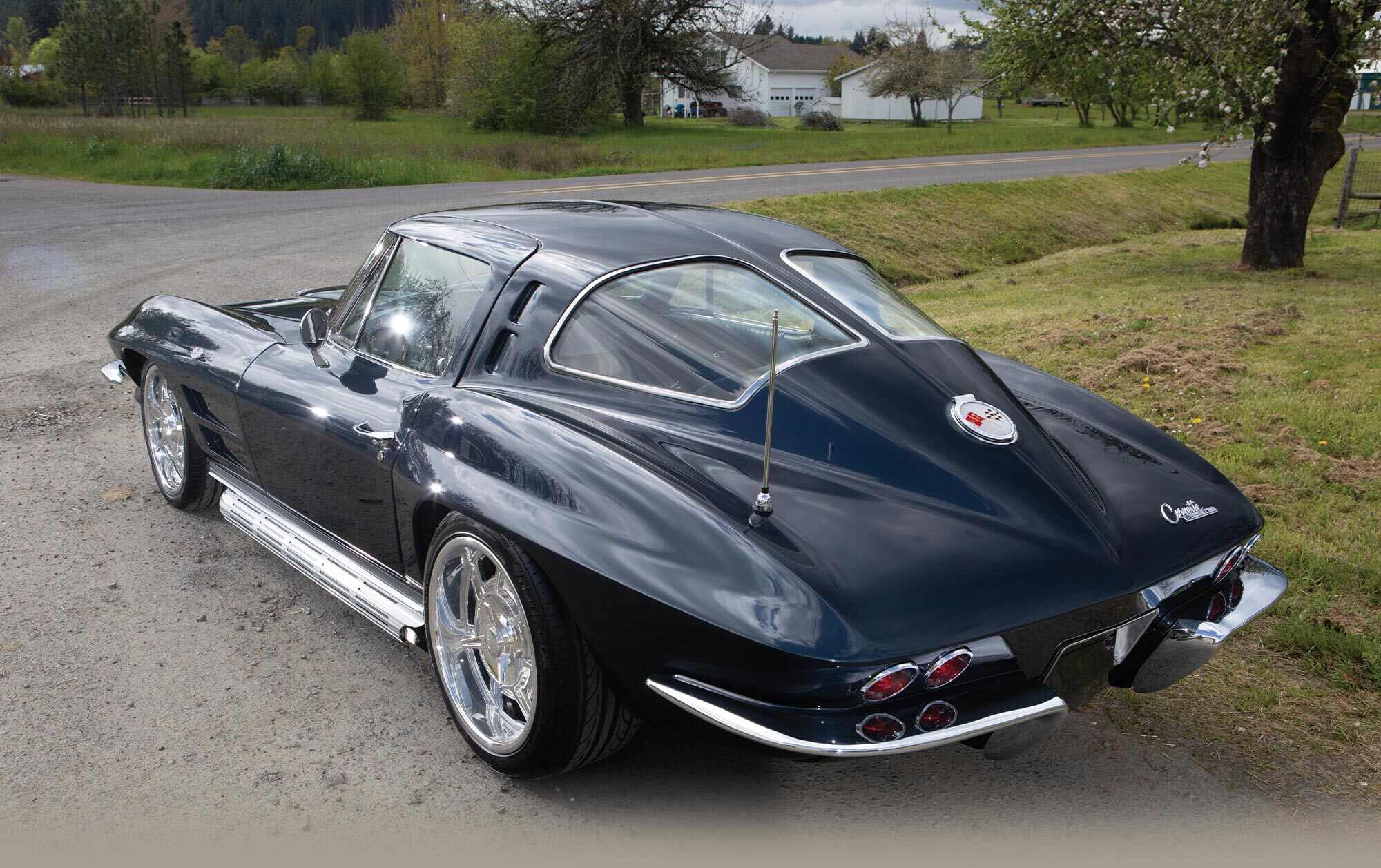 three quarter back view of Sam Smith's black '63 Corvette Sting Ray parked on a road side