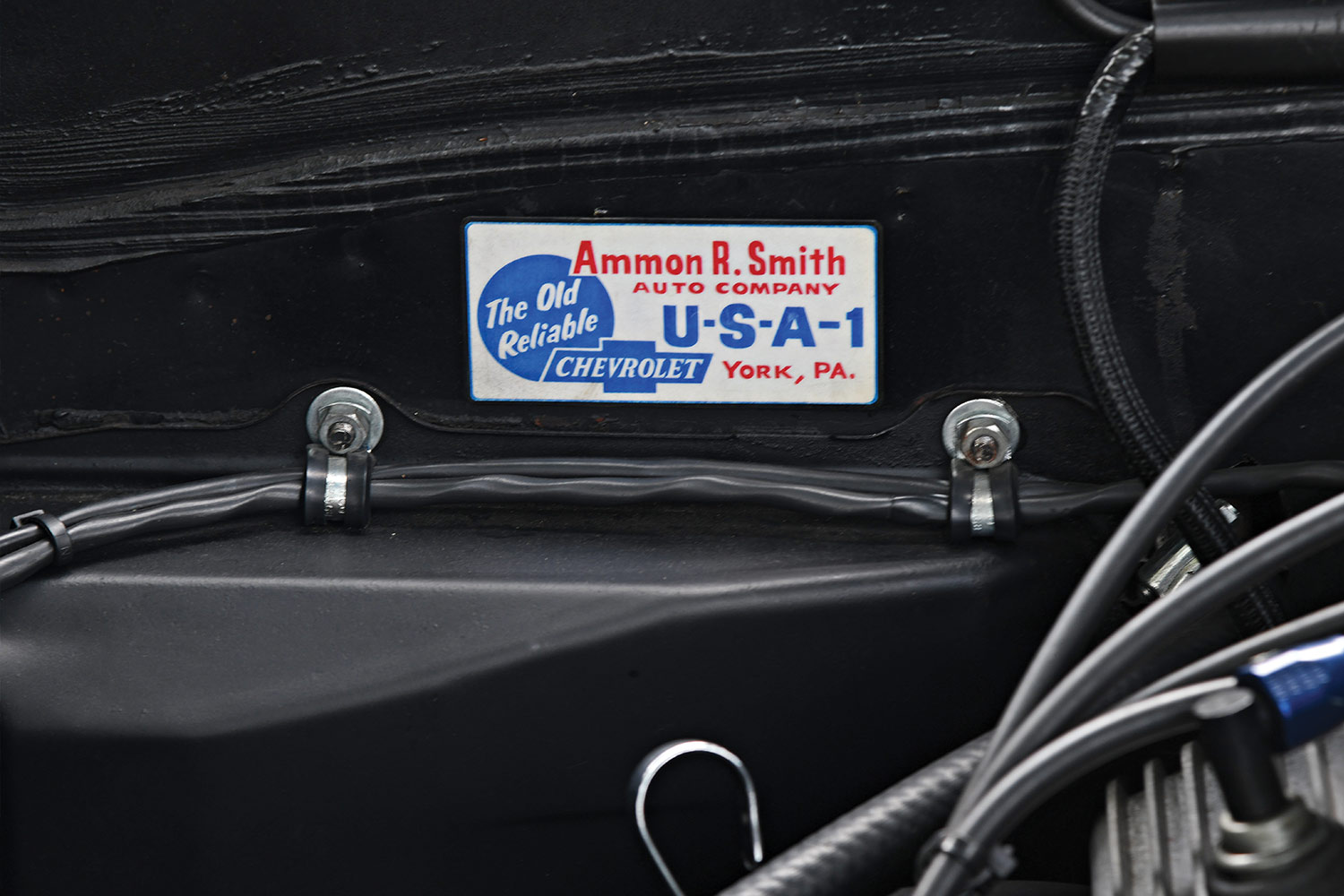 close view of an Ammon R. Smith Auto Company sticker among the '67 Camaro's engine components