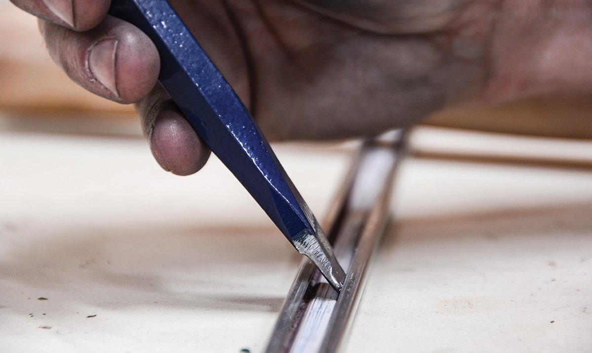 The trim repair kit came with three chasing chisels of different sizes. Due to this extremely tight spot, we modified the chisel to fit into the channel, but then rounded the edges so that it still works as designed. Very small taps make a big difference in the aluminum, and you don’t want any sharp edges that could puncture it.