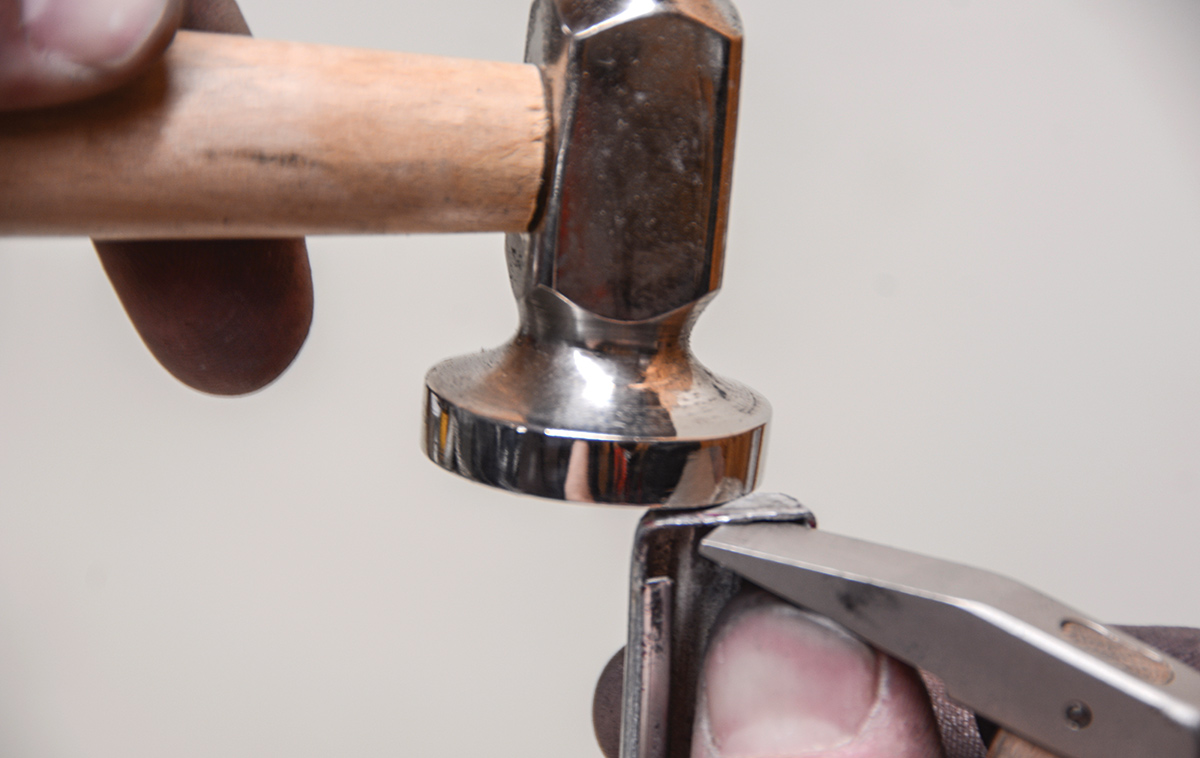 The chisel end of the trim hammer is now being used as a small dolly on the end of the trim. Nice, flat ends will give us clean lines once the trim is installed on the car. Luckily, the ends of our trim are not broken, as that would require some intricate soldering to repair the crack or split in the aluminum.