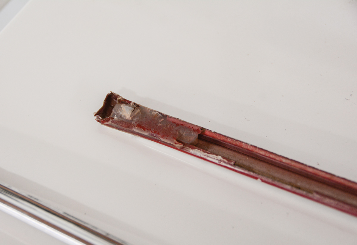 We also noticed a few areas where the trim had been glued onto the body with silicone due to missing or damaged clips. Our first step is to scrape and clean out the gunk inside the channel and start stripping the paint.