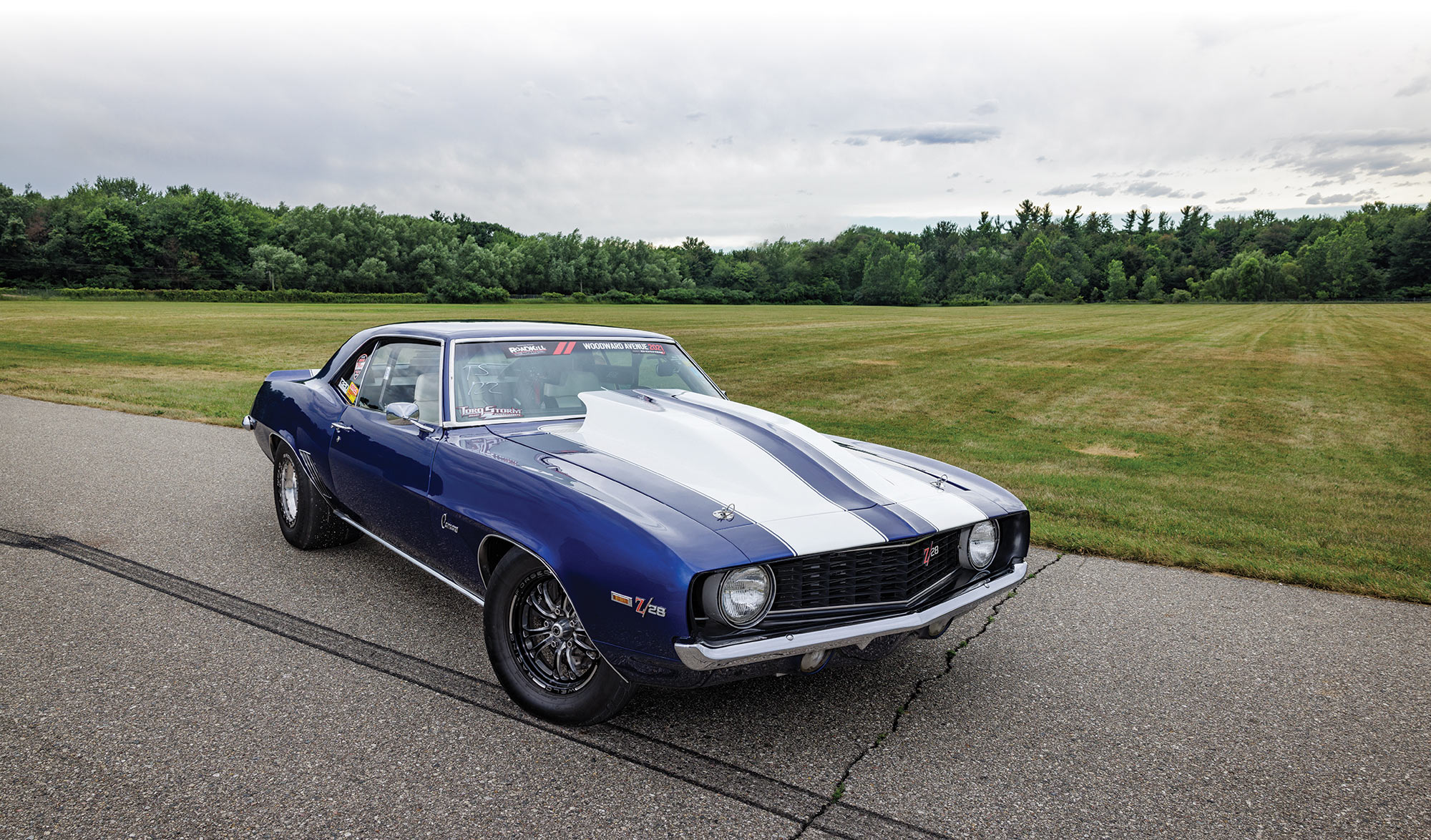 Front 3/4th view of Camaro with large field and woods in background