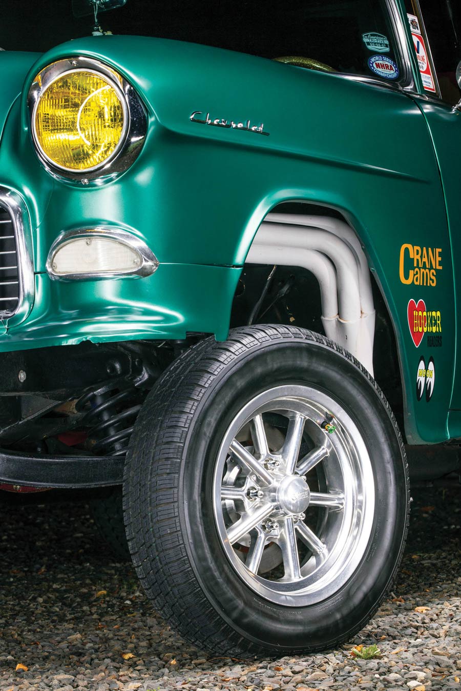 close up of a headlight, front tire on an emerald green '55 Chevy