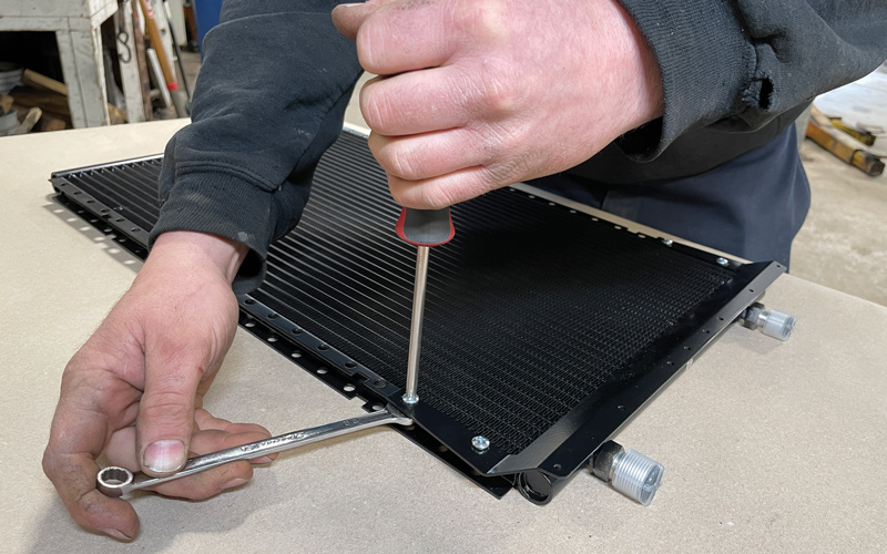 With the parallel-flow condenser laid on the bench, the supplied mounting brackets were set in place using the provided hardware, starting with the universal drier bracket (pictured here).