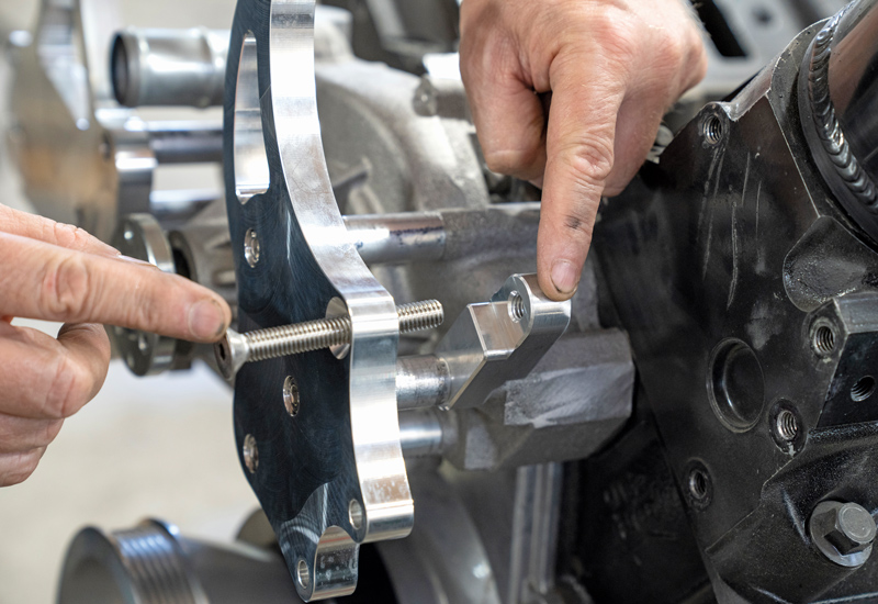Remove the two temporary bolts from the driver side of the water pump, then use two of the 2.25-inch spacers and bolts through the driver side bracket and water pump. Once again, use some antiseize on the threads and tighten enough to hold in place.