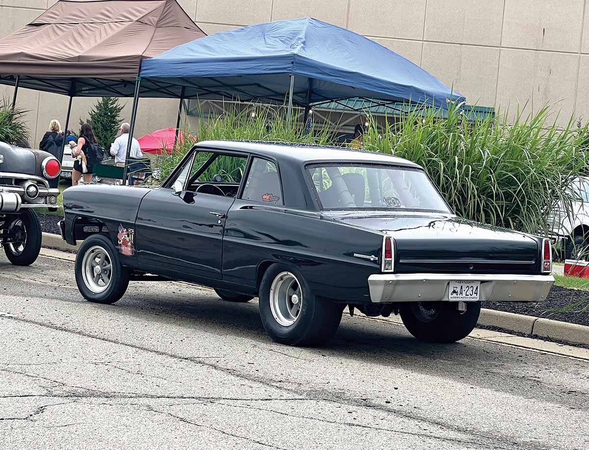 Close-up photograph perspective of a black colored Chevrolet car parked on the curb nearby some tents at the 54th annual NSRA Street Rod Nationals