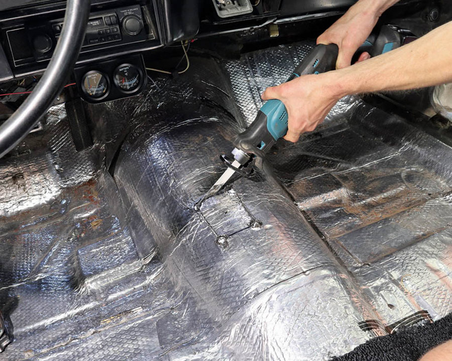 From under the car, we drilled a single hole in the center of our measured shifter location. Then, from inside the car, we measured and marked what we wanted to cut. We drilled pilot holes followed by a uni-bit to give a starting point for our reciprocating saw. We only cut a small rectangle out; just enough to get in the ballpark and start test-fitting with the engine and transmission in place.