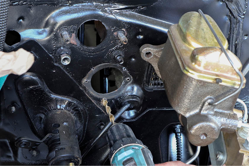 Next we moved onto installing the clutch master cylinder. We unbolted the brake master cylinder to give us more working room, then removed the factory cover underneath. Using the backing plate for the clutch master as a template, we drilled the three pilot holes needed.