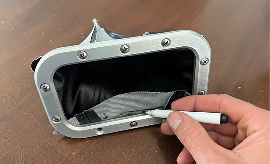 It was onto the final touches: reinstalling the shifter boot and trim ring. To fit the boot to the trim ring, we flipped the fabric inside out and folded the edges in half up against the underside of the trim ring. Then we used a pick to poke holes for the screws and made marks to trim away the excess fabric.