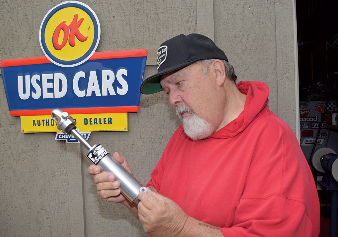 Older man inspecting a car shock that he is holding
