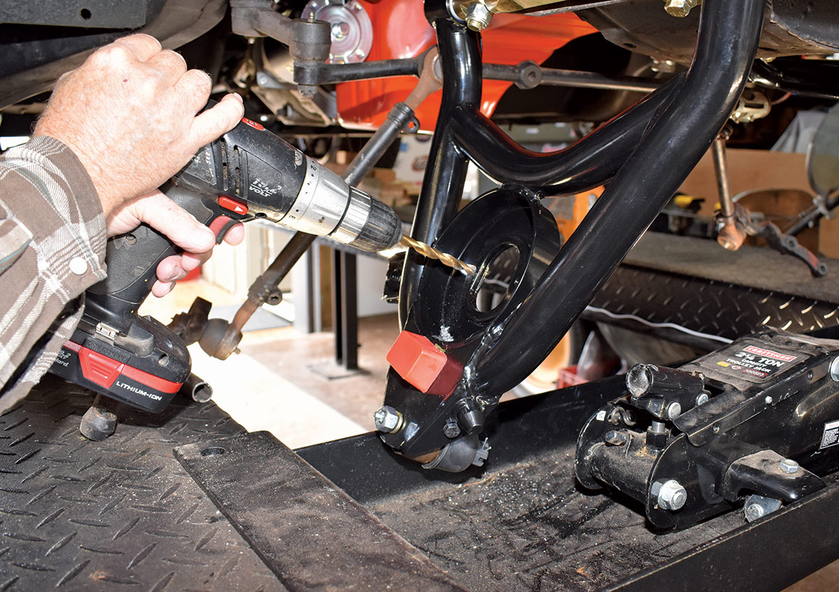 Man's hands using a drill on a Chevy control arm