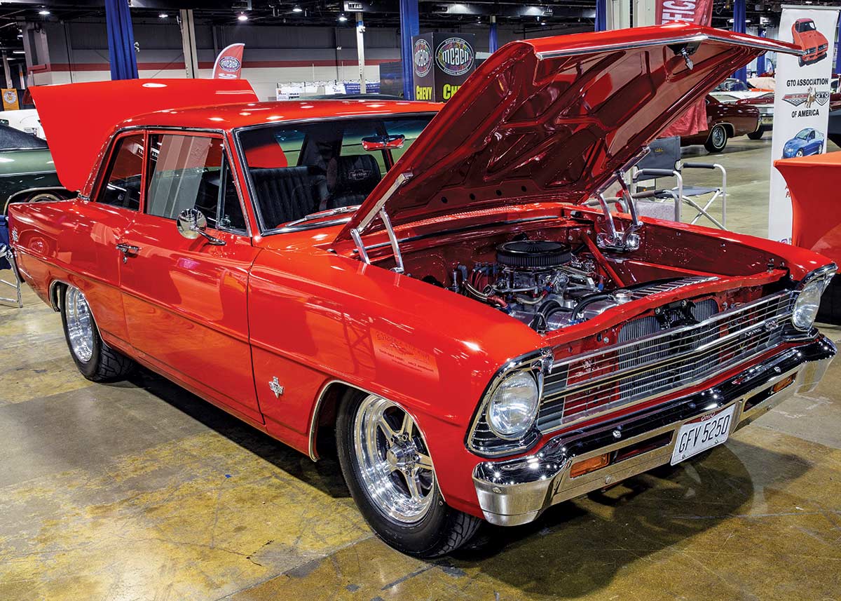 Close-up photograph perspective of a vintage red Camaro car with its hood and trunk open in a display area of a showroom floor
