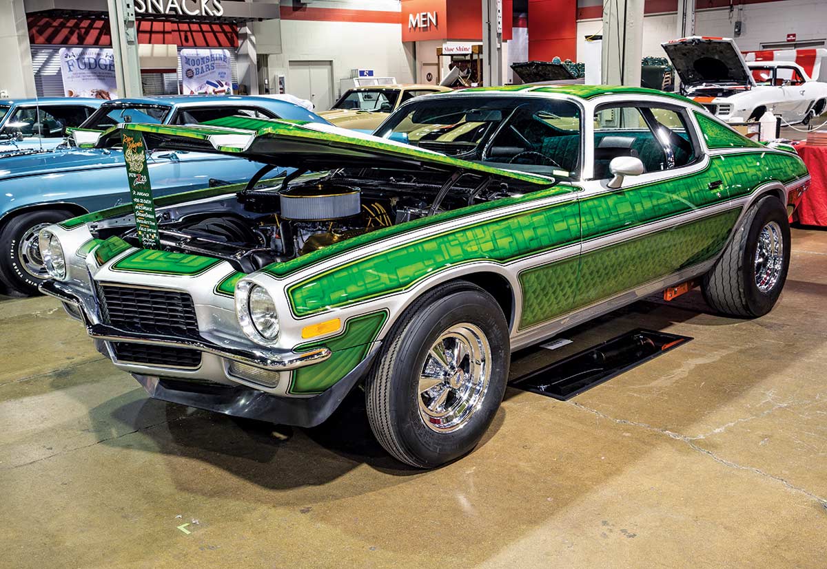 Close-up photograph perspective of a green/white vintage custom-themed ’70 Camaro Z28 car in a display area of a showroom floor
