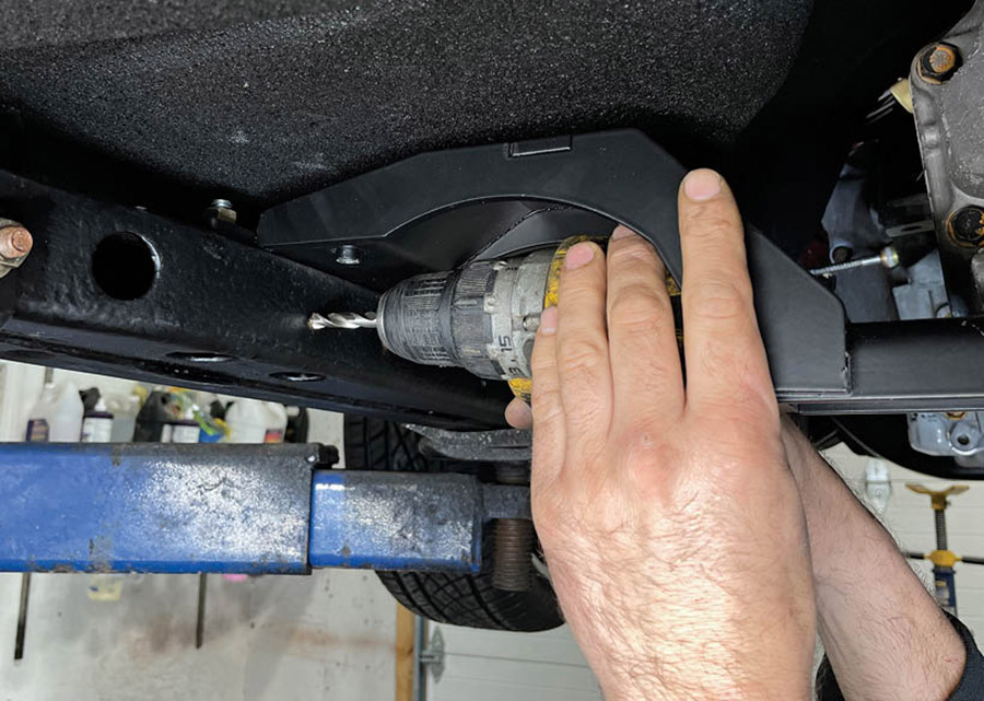 With the brackets removed, start with a pilot hole and gradually drill the mounting holes to the final 7/16-inch hole required.