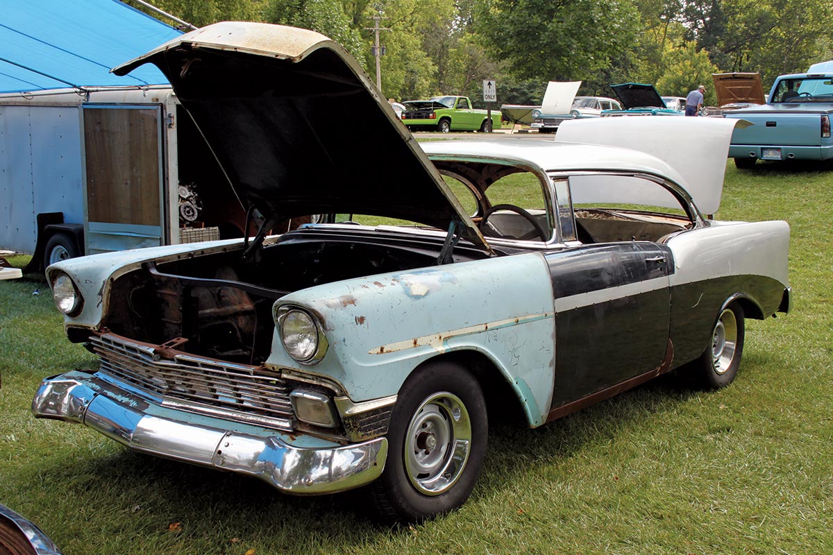 Old Chevy in the grass at a show, with trunk and hood open, mismatched body paint colors